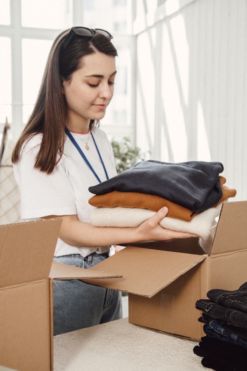 Woman Arranging Boxes of Clothing Donations